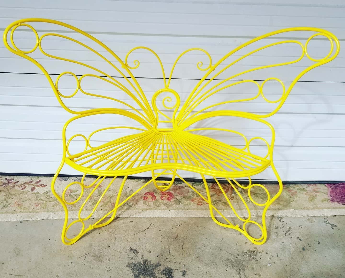 A yellow butterfly shaped bench sits in front of a garage door