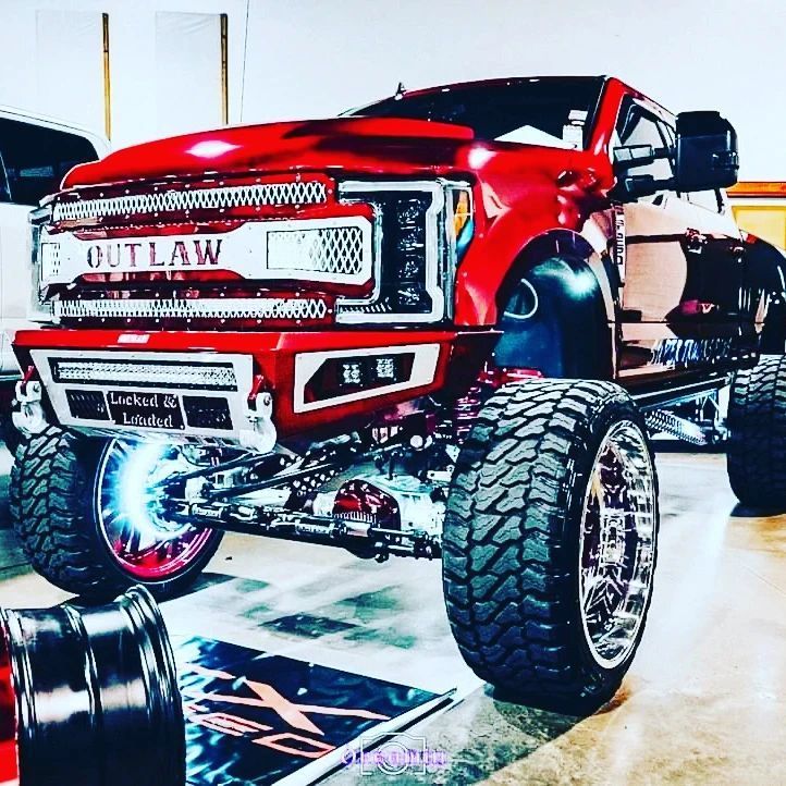 A red outlaw truck is parked in a garage