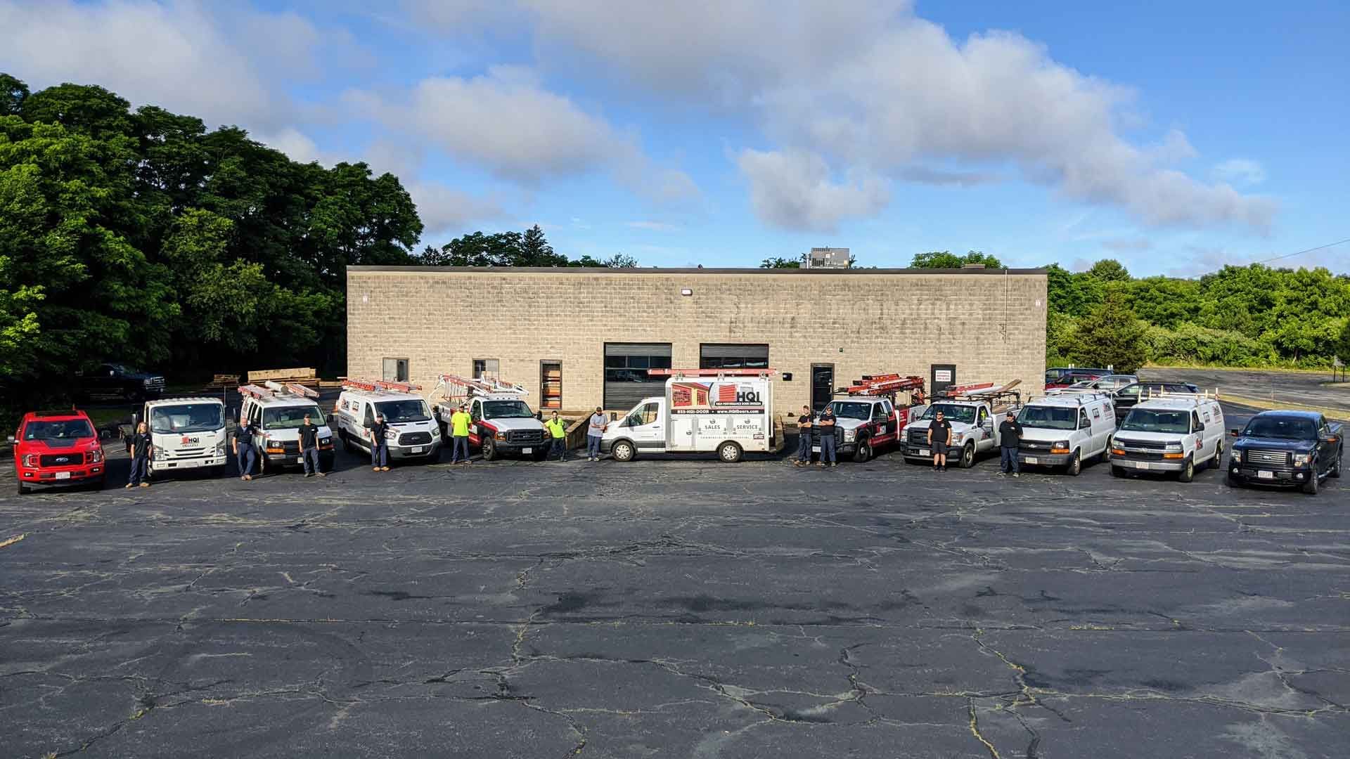 A row of work vehicles parked in front of a brick building on a sunny day.