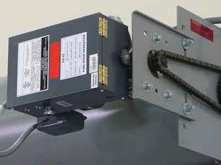 Motorized fire door mechanism with metal components, chain, and control box.