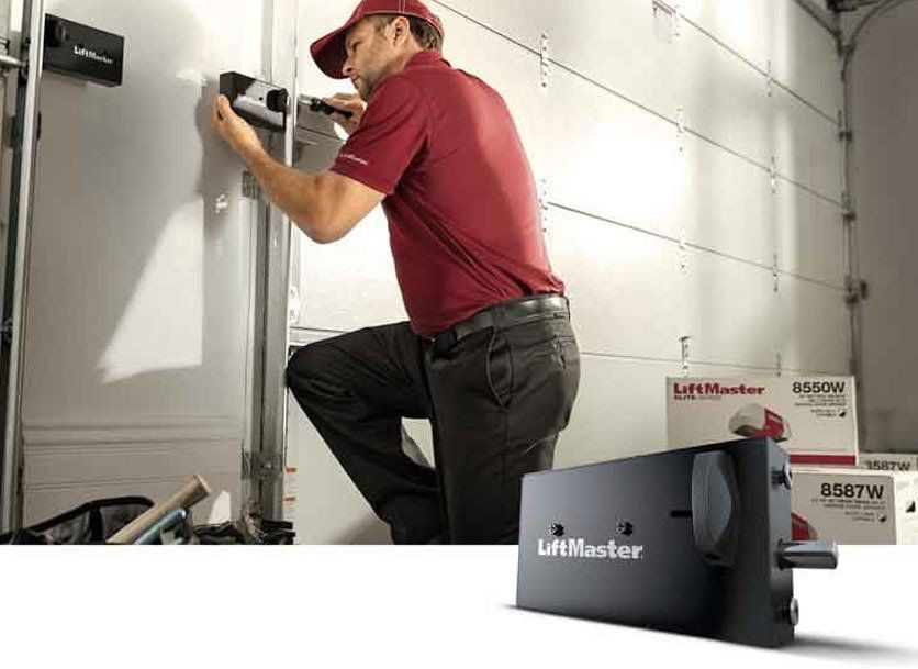A man in a red shirt installing a LiftMaster garage door opener in a garage.