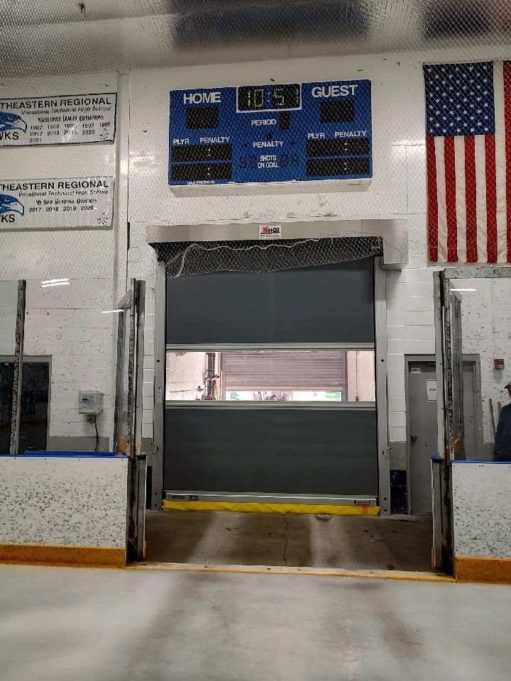 Hockey rink with a scoreboard, large garage-style door, and American flag.