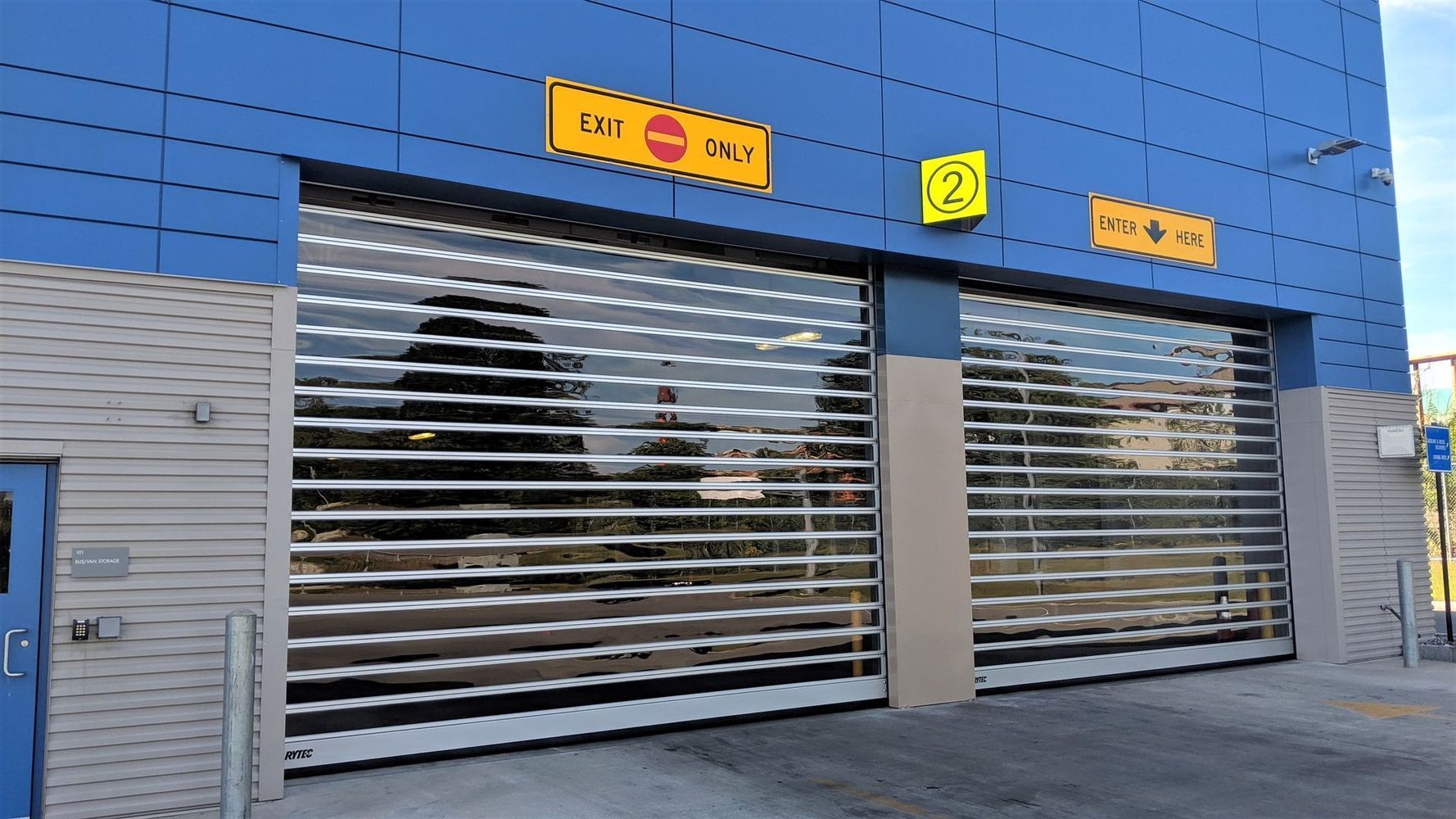 Blue building with two see-through rolling doors, each with a height restriction sign above.
