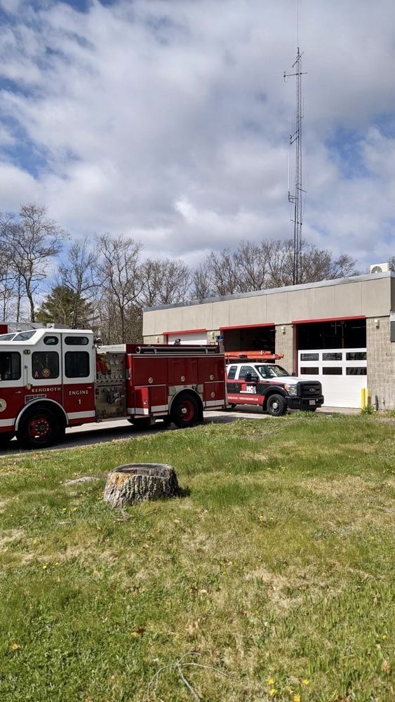 Fire trucks parked at a fire station with an antenna tower.