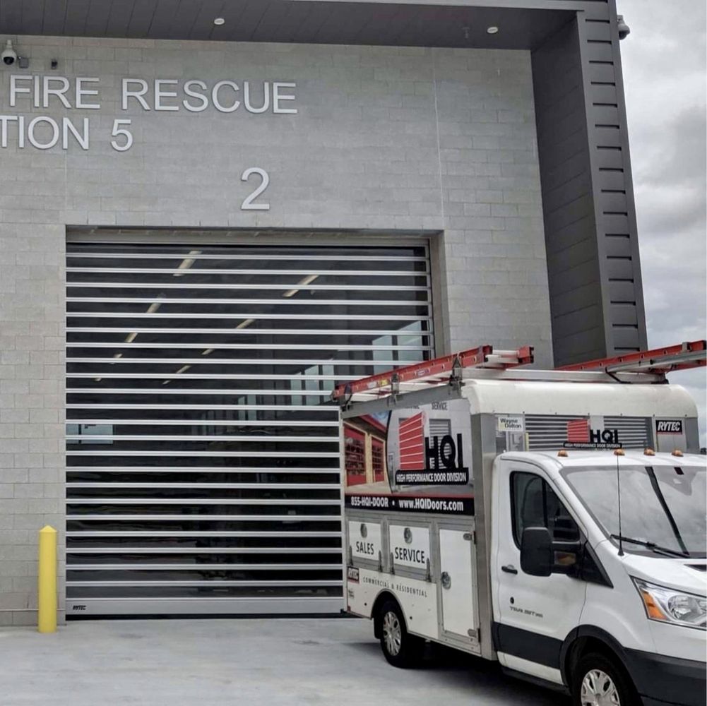 Fire Rescue Station 5 with a roll-up door. A service van with a ladder parks in front.