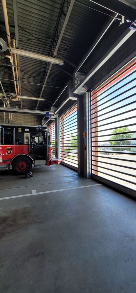 Fire truck inside a fire station with large, open doors.