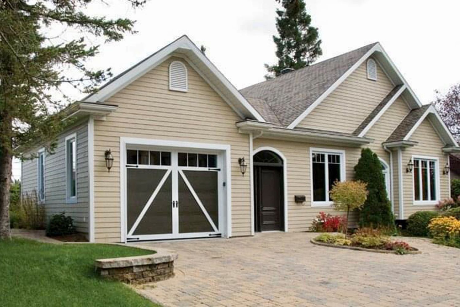 Tan house with a garage and a brick driveway.