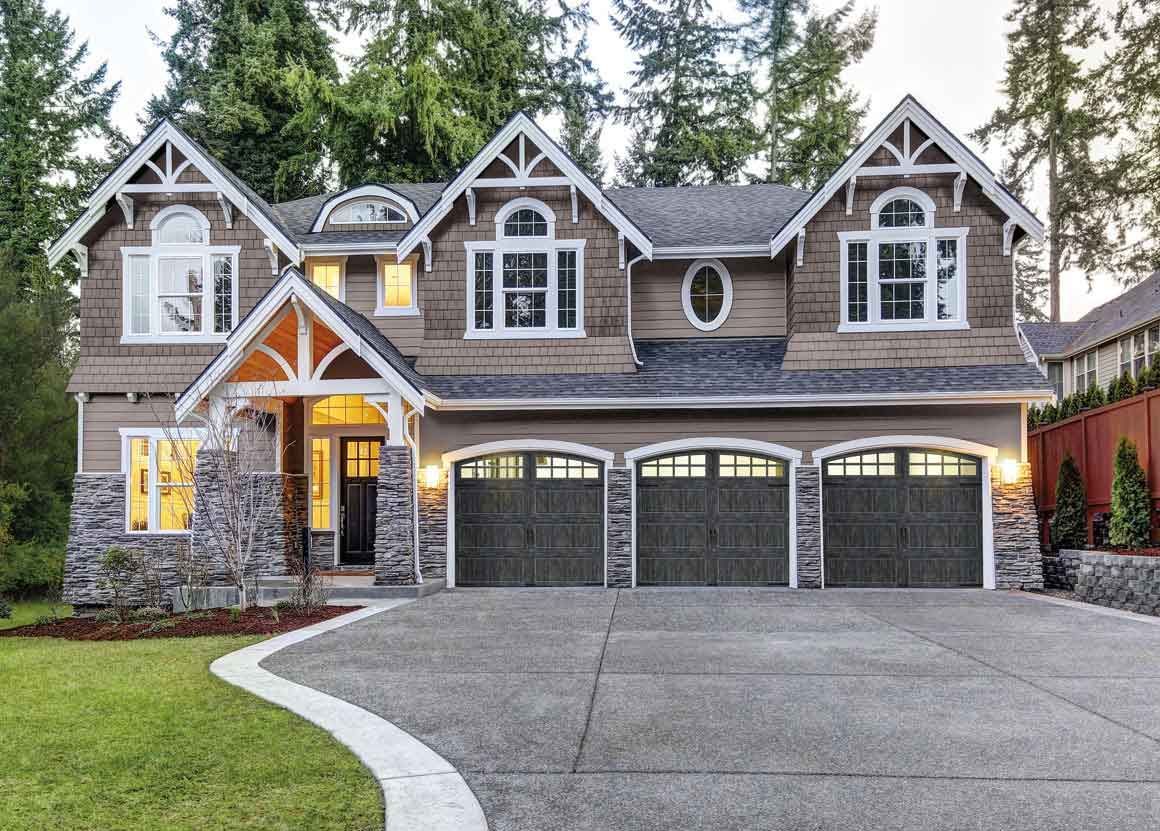House exterior with three-car garage, brown siding, arched windows, and a curved driveway.