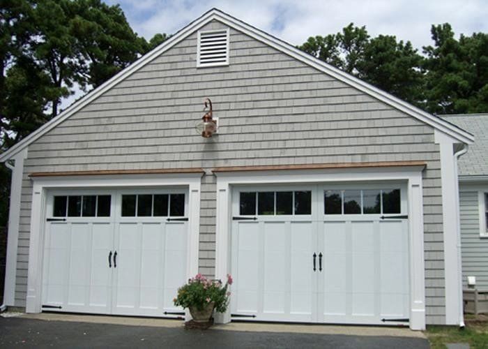 Two-car garage with white doors, light gray shingles, and a small decorative light.