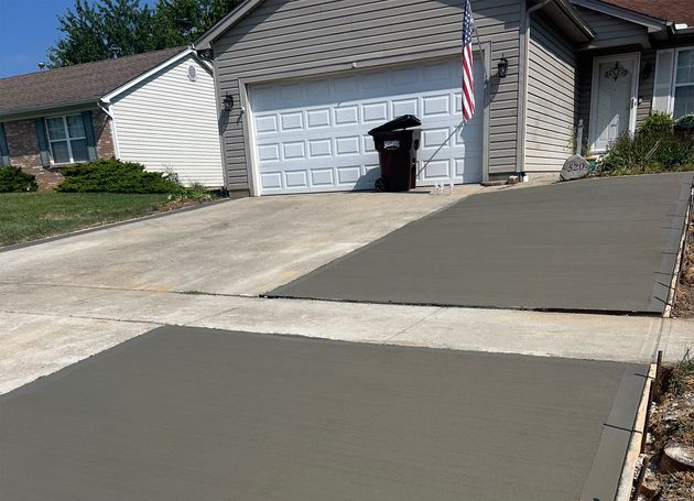 House with a freshly paved driveway and sidewalk, garage, and an American flag by the front door