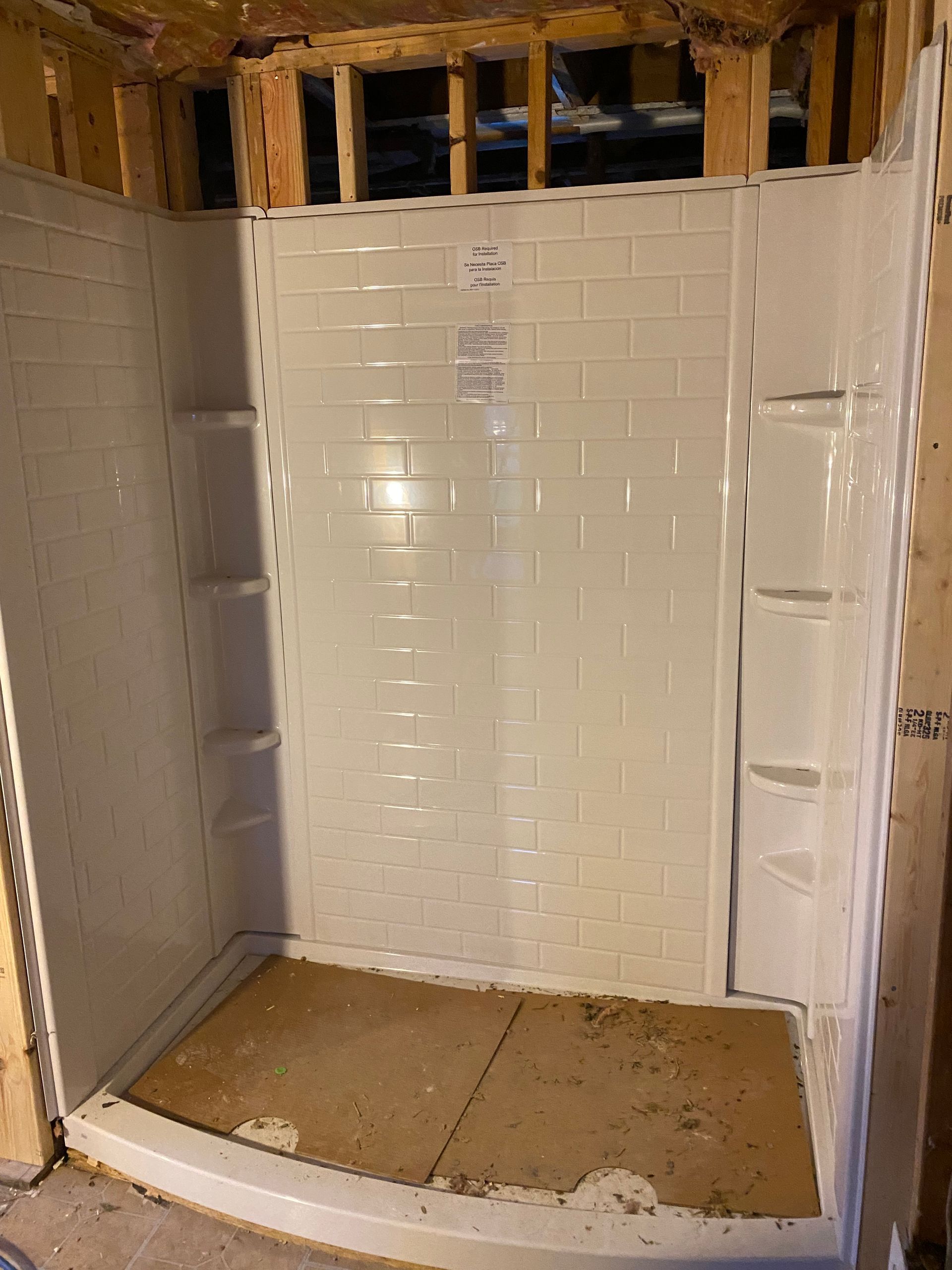 Partially tiled shower stall under construction with exposed studs and unfinished floor