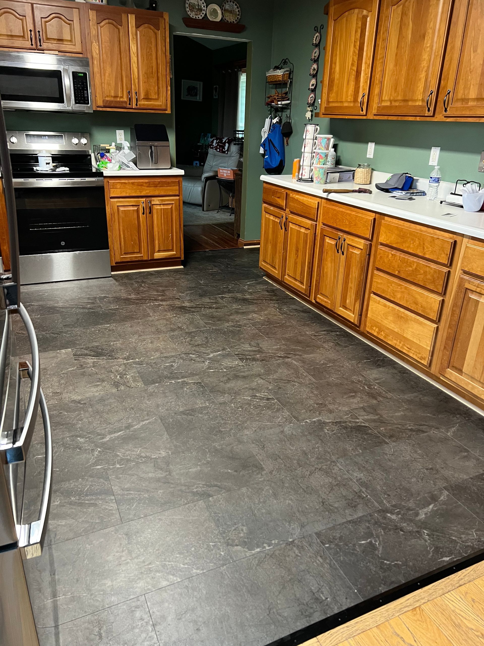 Kitchen with wooden cabinets, black appliances, and a dark stone floor leading to a doorway.