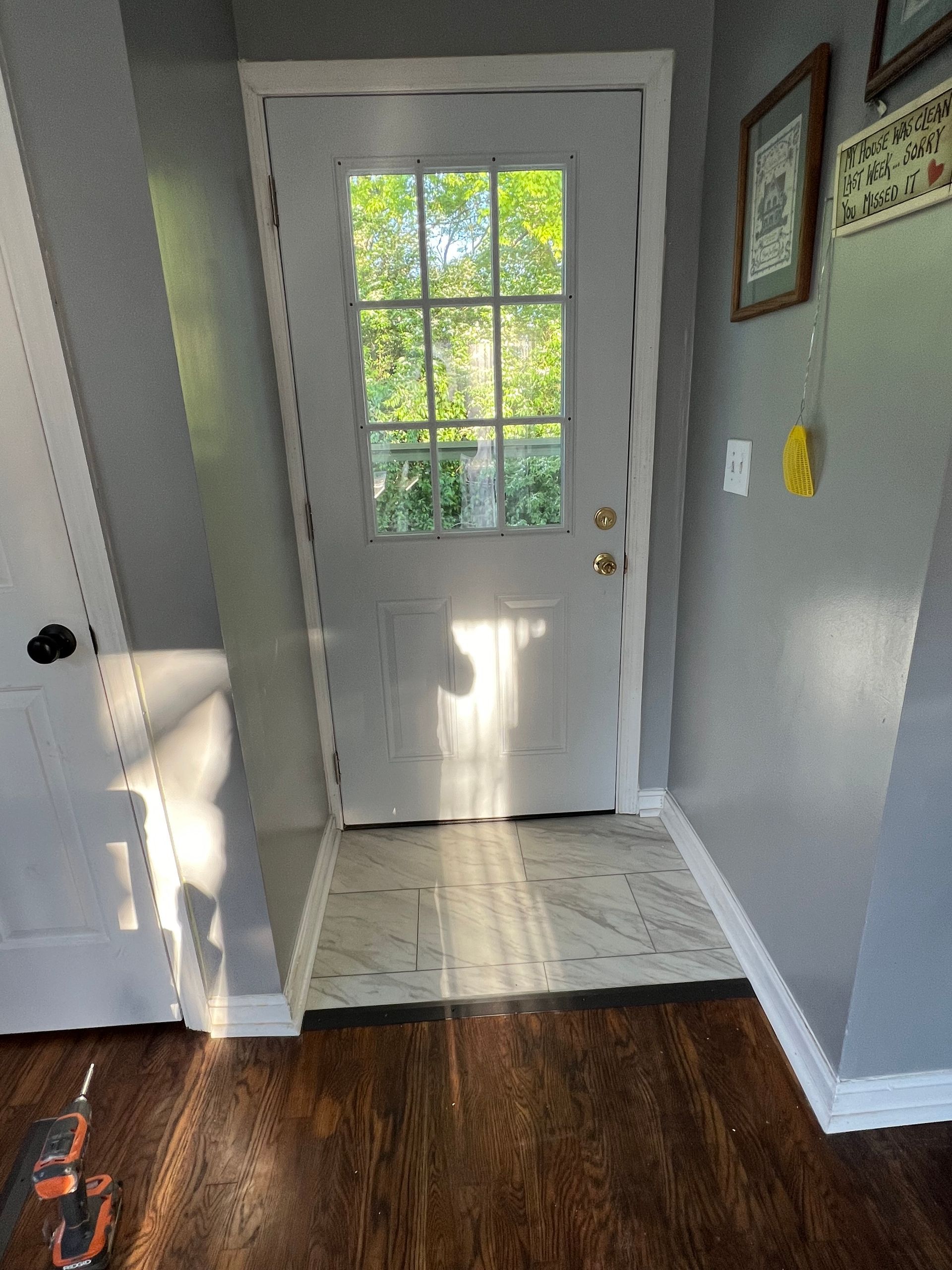 Hallway with dark wood floor, gray walls, and a white door with glass panes at the end.