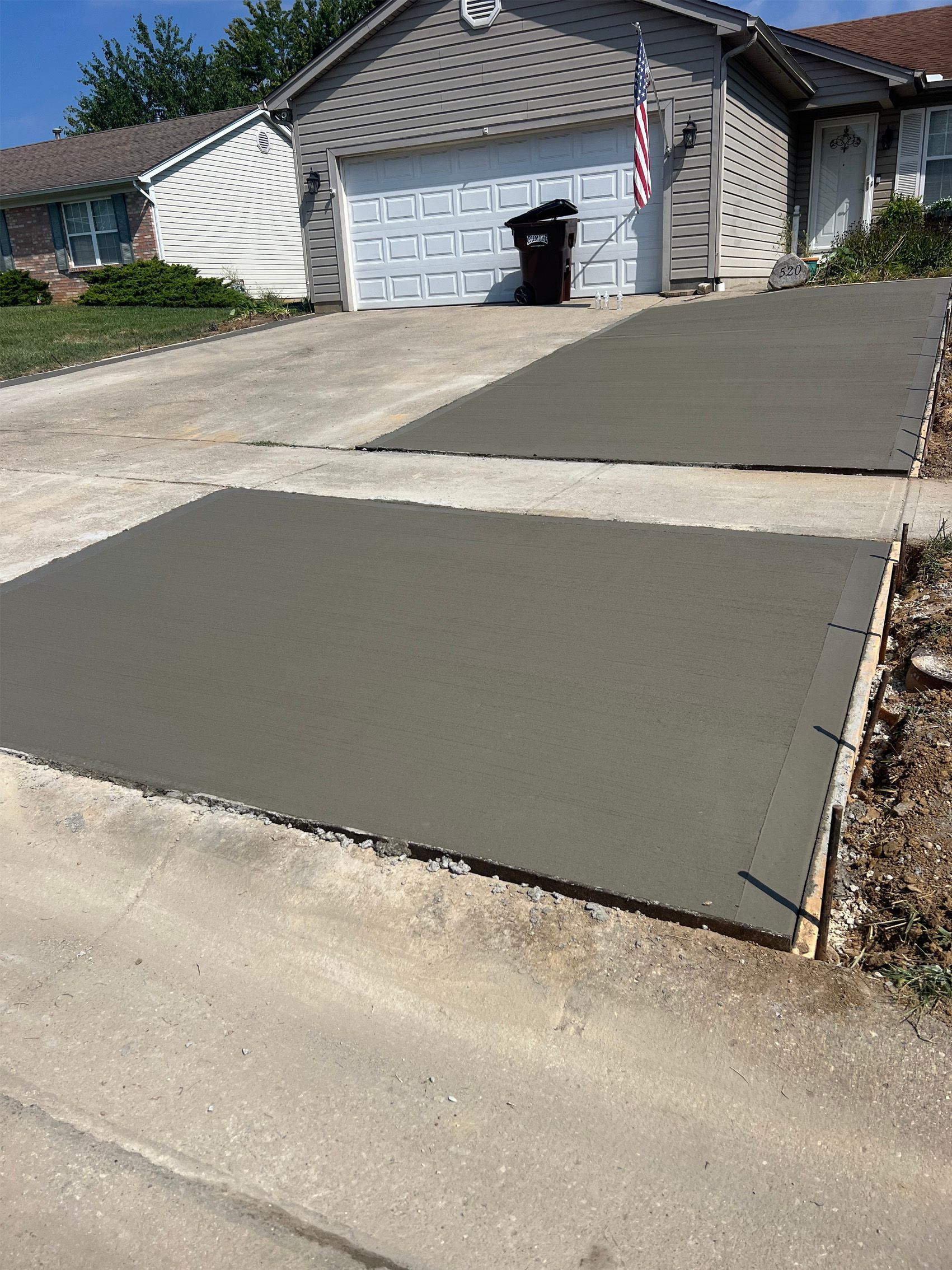 Driveway leading to a garage, with fresh dark concrete and a curb cut at the street.