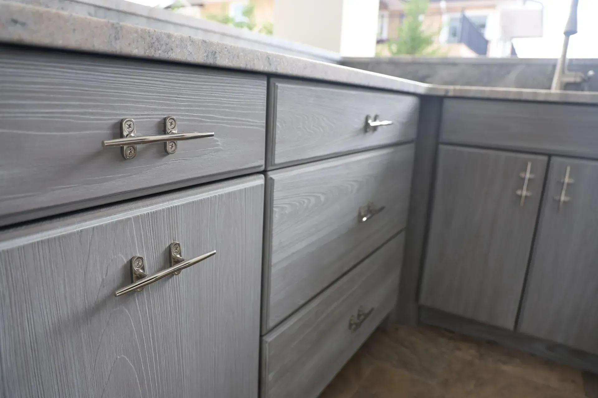 Grey-stained wooden kitchen cabinets featuring unique nautical cleat-style drawer pulls and cabinet handles.