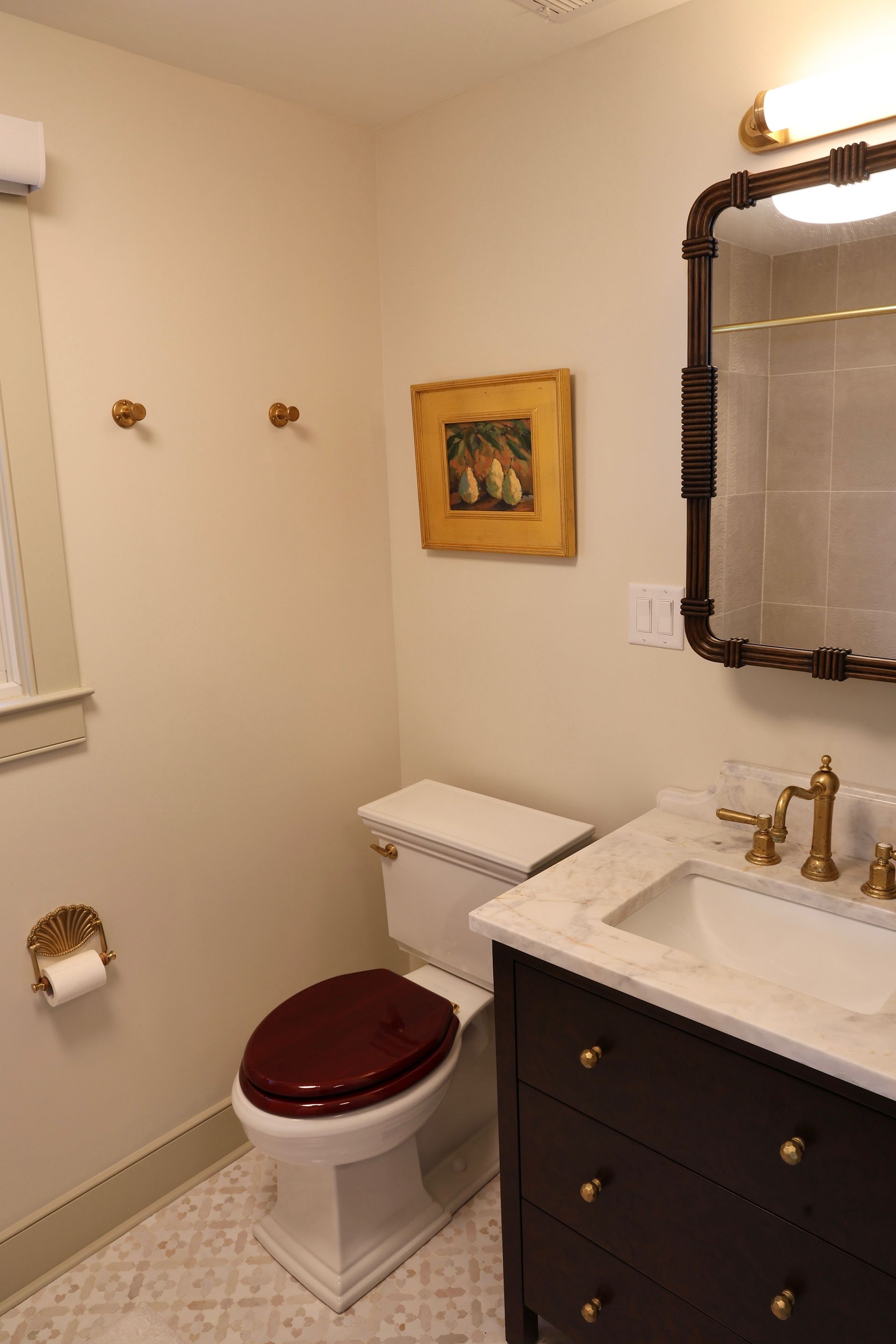 Small bathroom with toilet, vanity sink, mirror, and wall art in beige tones.