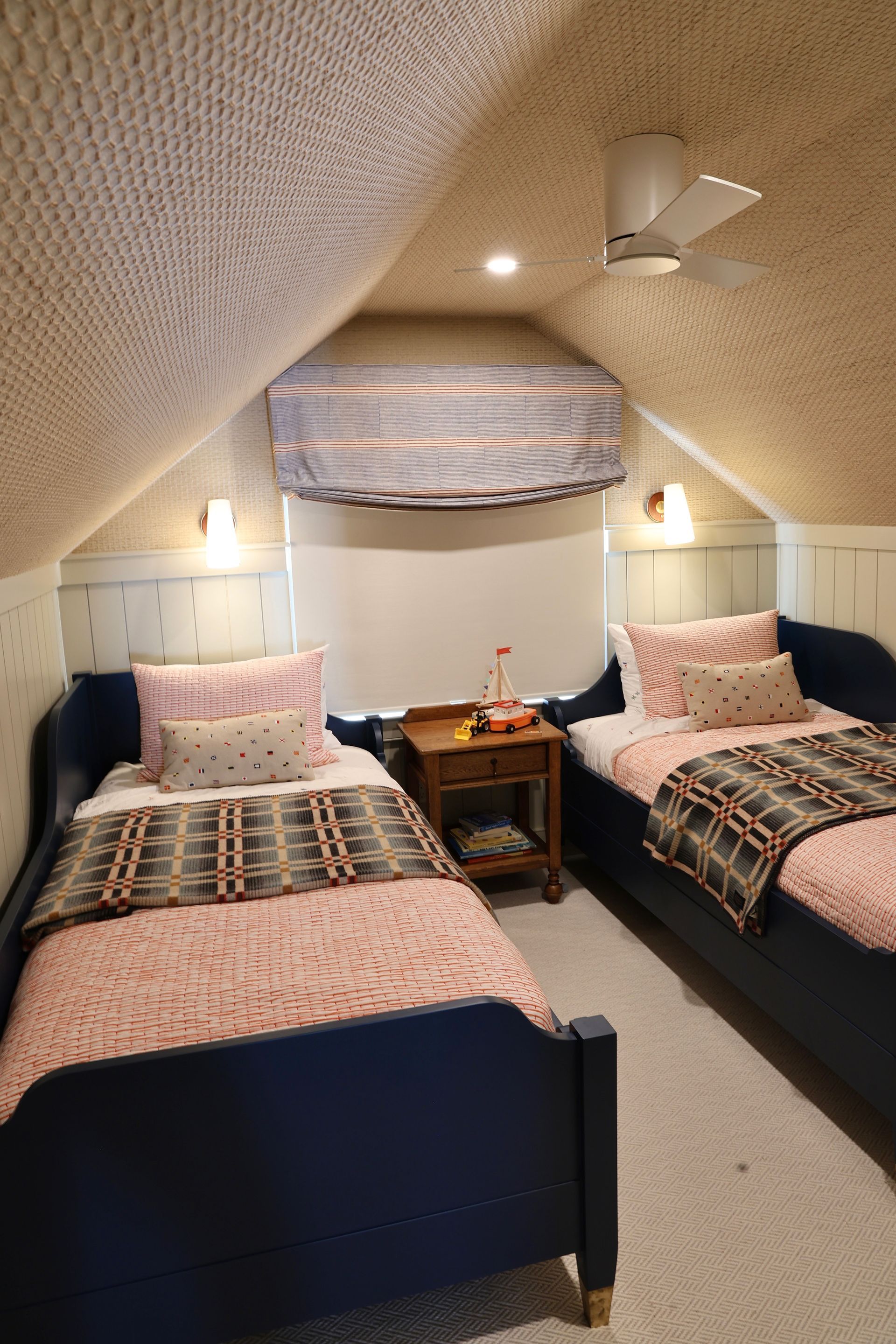 Narrow bedroom with two single beds, patterned bedding, skylight, and a small window seat.