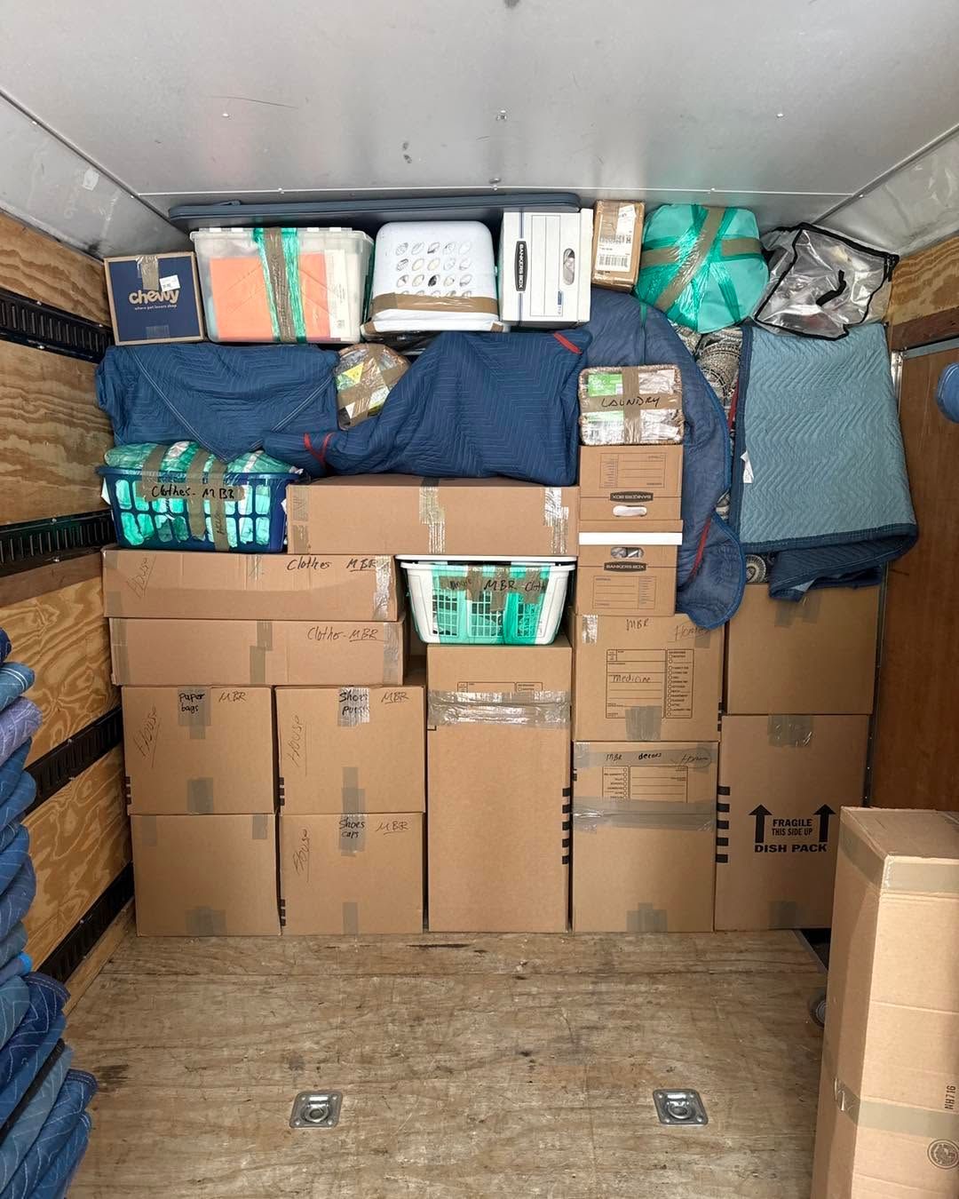 Packed moving truck filled with stacked cardboard boxes and bundled household items
