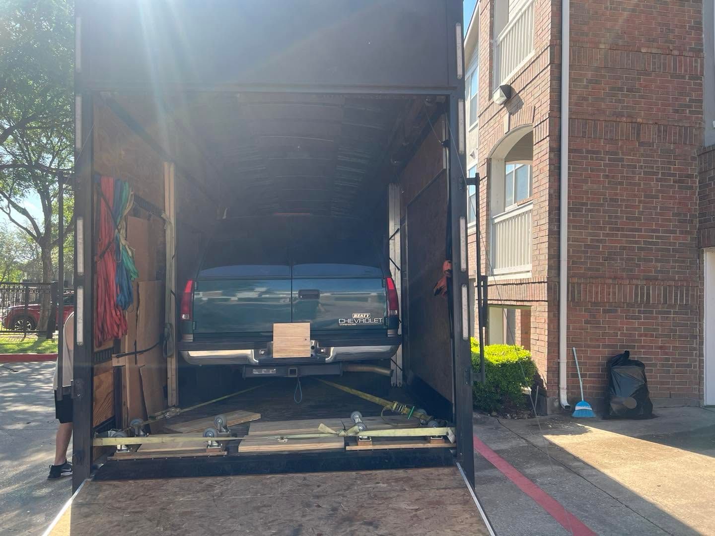 Pickup truck inside a moving truck at a brick building entrance