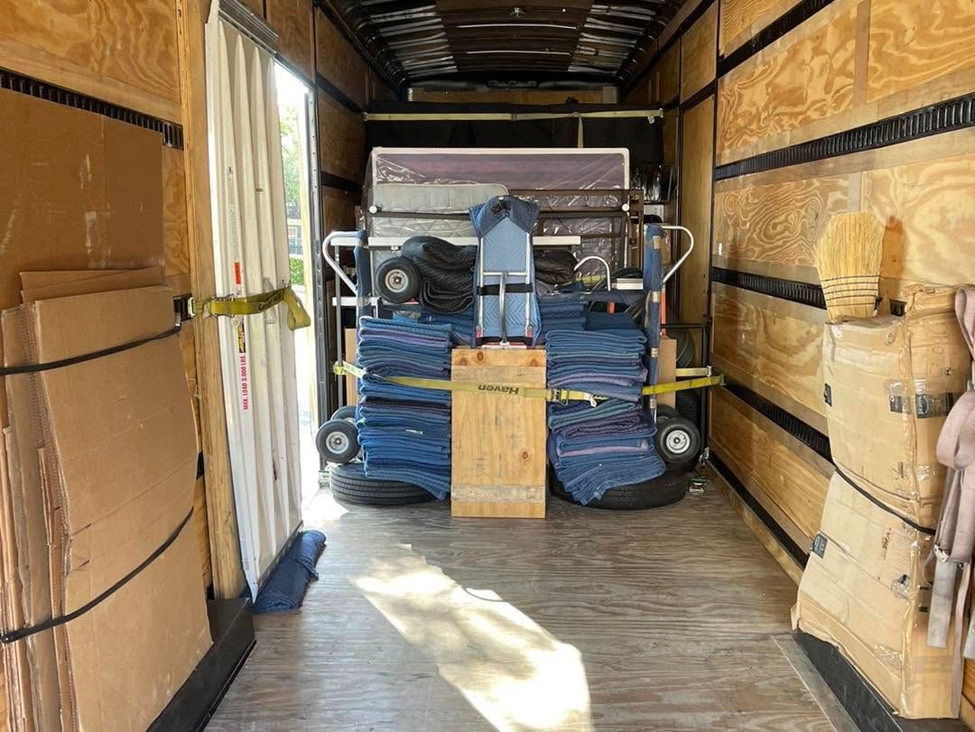 Large packed truck interior with wrapped furniture, boxes, and a strapped blue load secured for transport