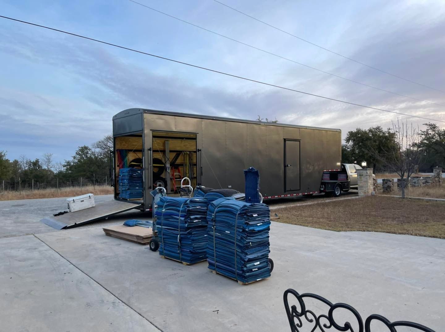 Construction site with a semi-truck, blue-wrapped pallets, and a large modular building in the background