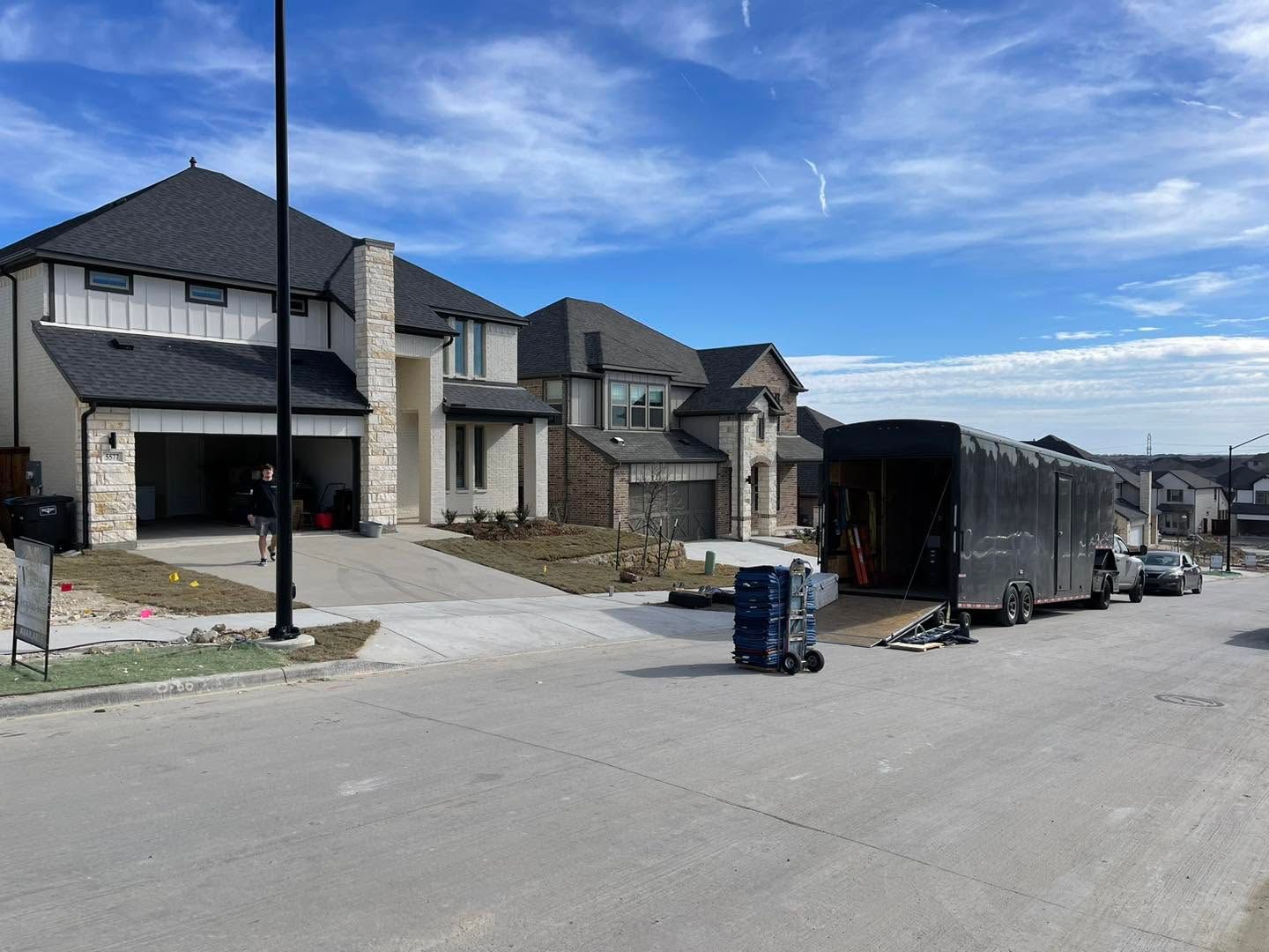 New homes under construction on a suburban street with dumpsters and building materials scattered along the road