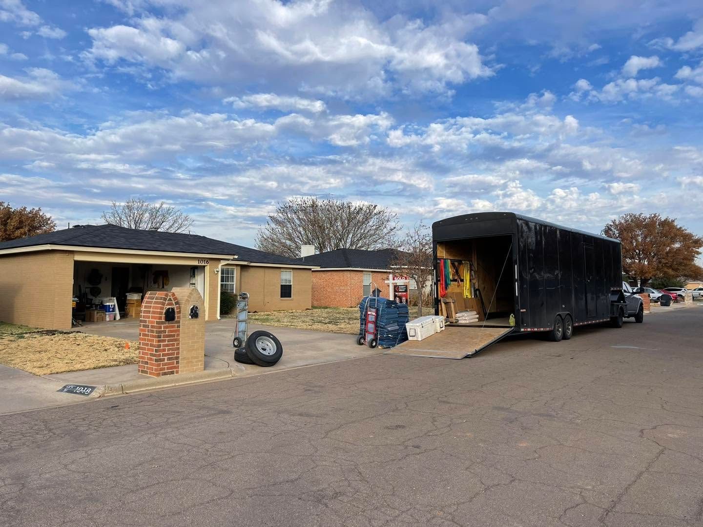 Single-story building with a black moving truck and ramp parked outside on a cloudy day
