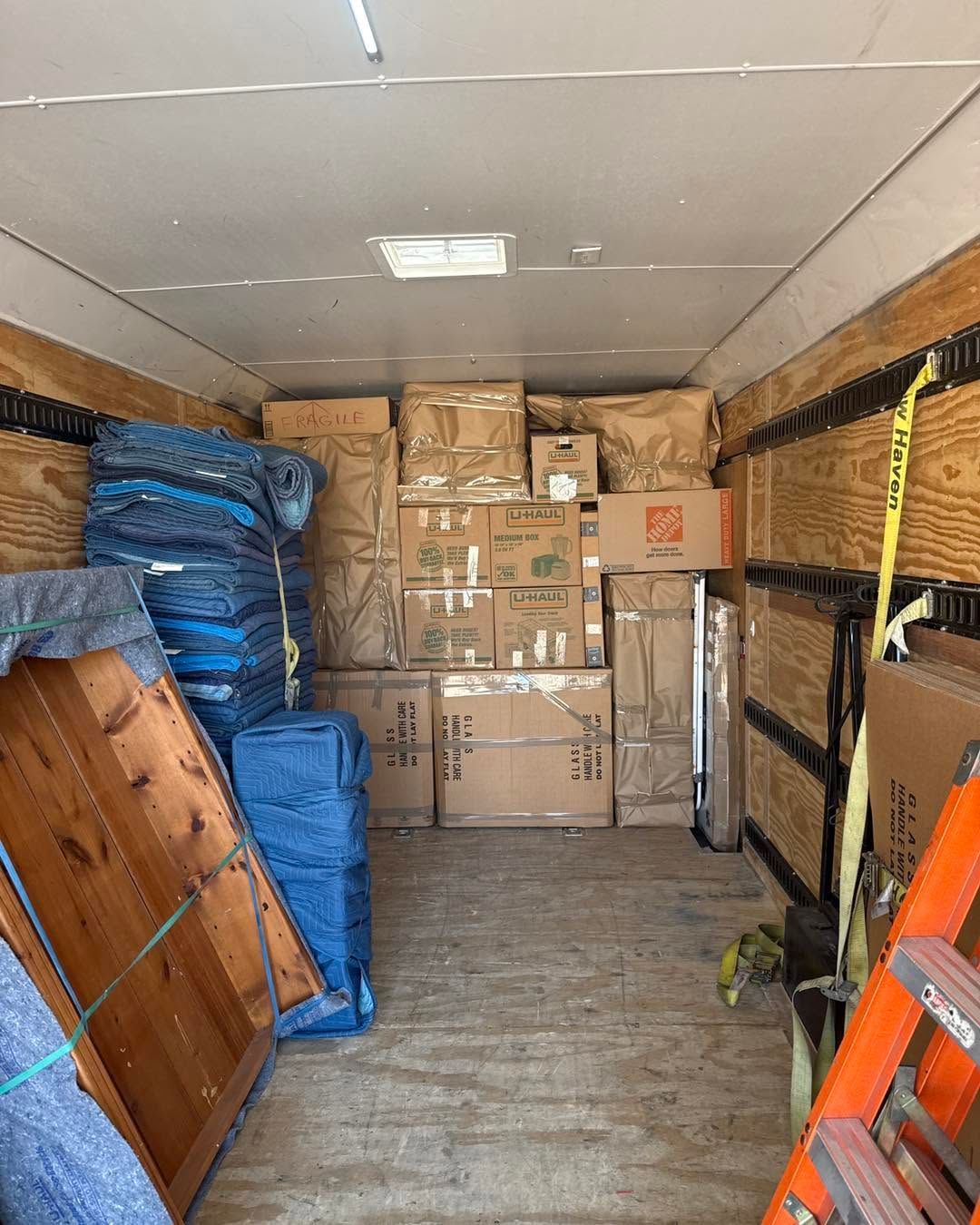 Box-packed moving truck interior with blue-wrapped items stacked along the sides