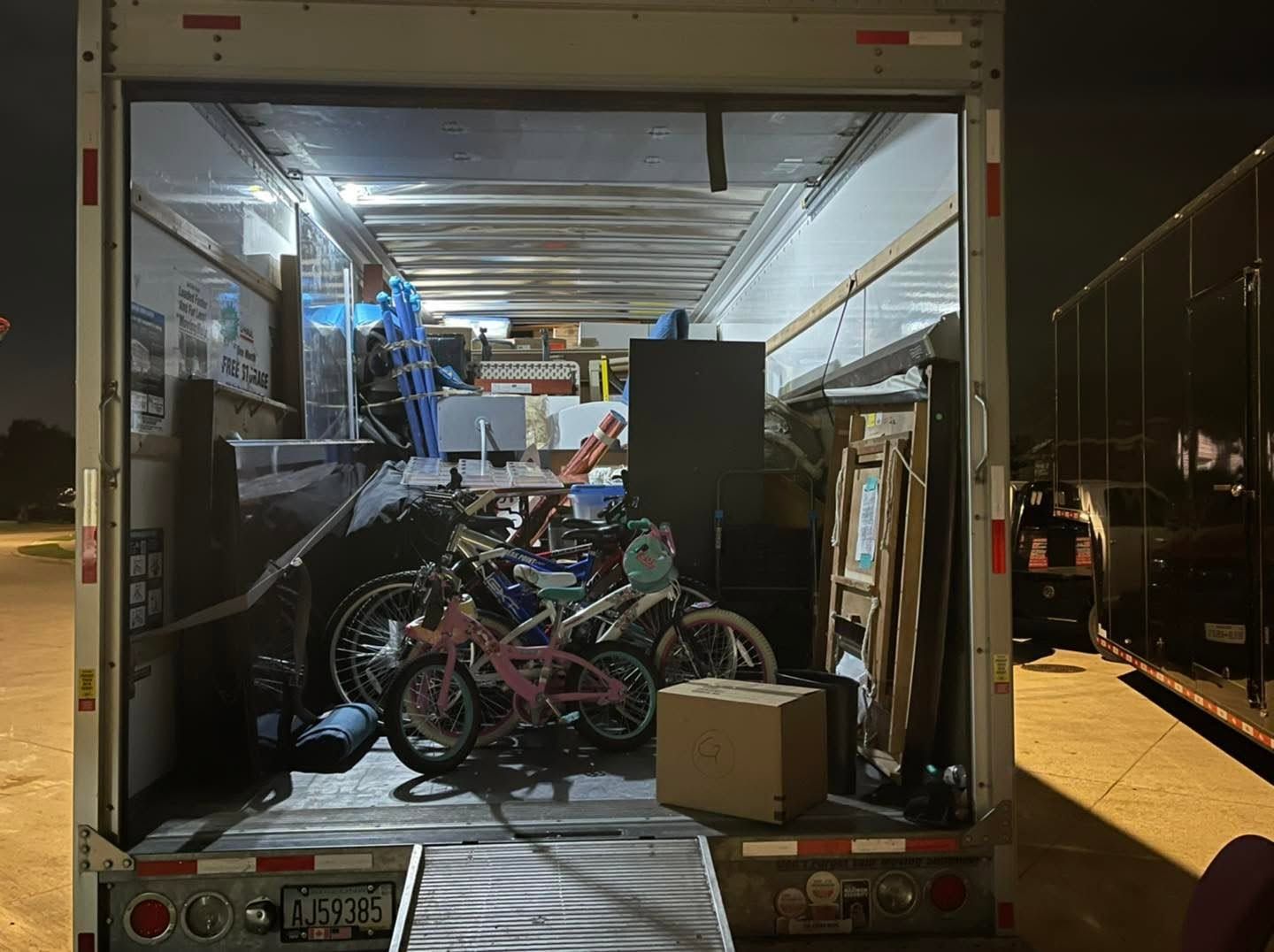Open truck with bicycles and boxes packed inside at night at a loading area