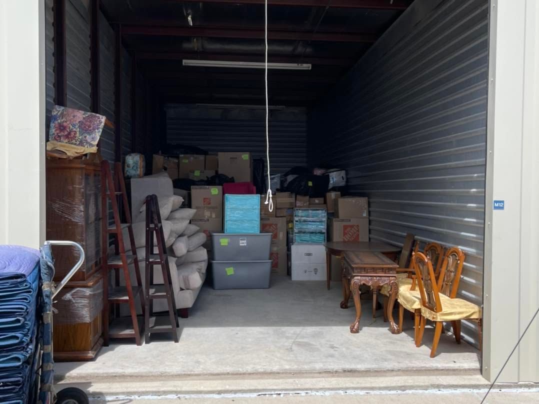 Open storage unit filled with stacked boxes, furniture, and miscellaneous items inside.
