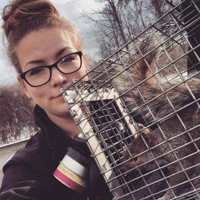 Woman with glasses holding a metal trap outdoors in a snowy setting