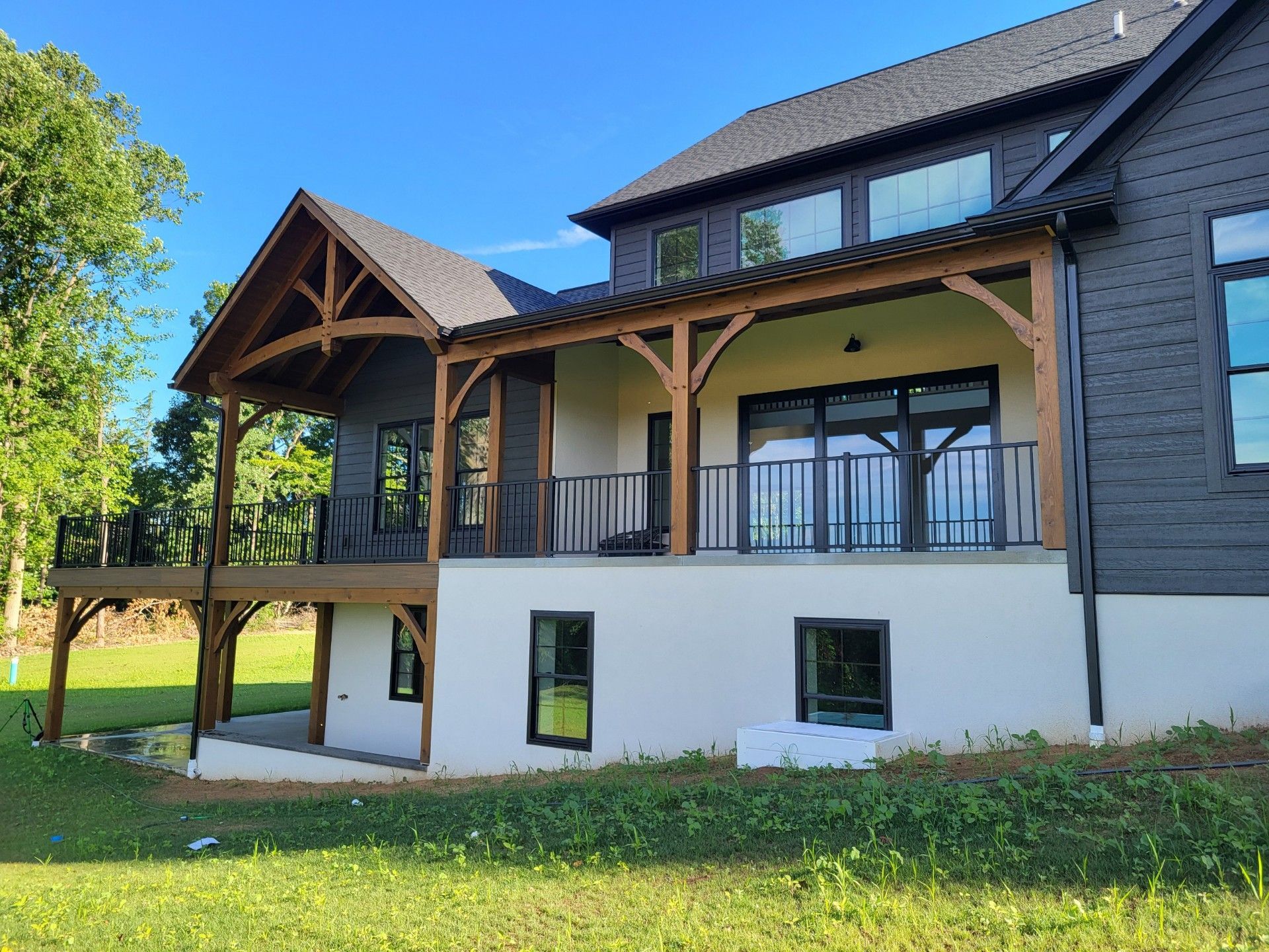 Modern two-story house with dark siding, white lower walls, and a covered wooden porch 