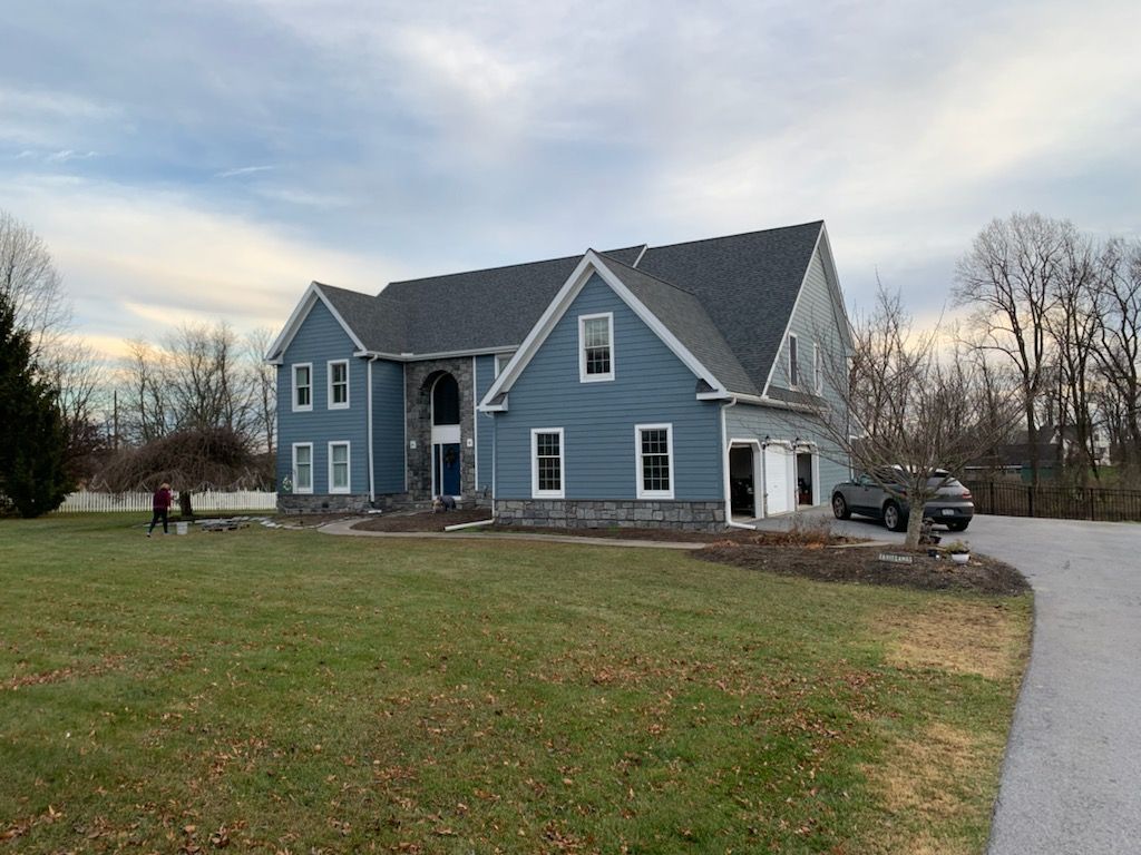 Blue two-story house with white trim and a driveway
