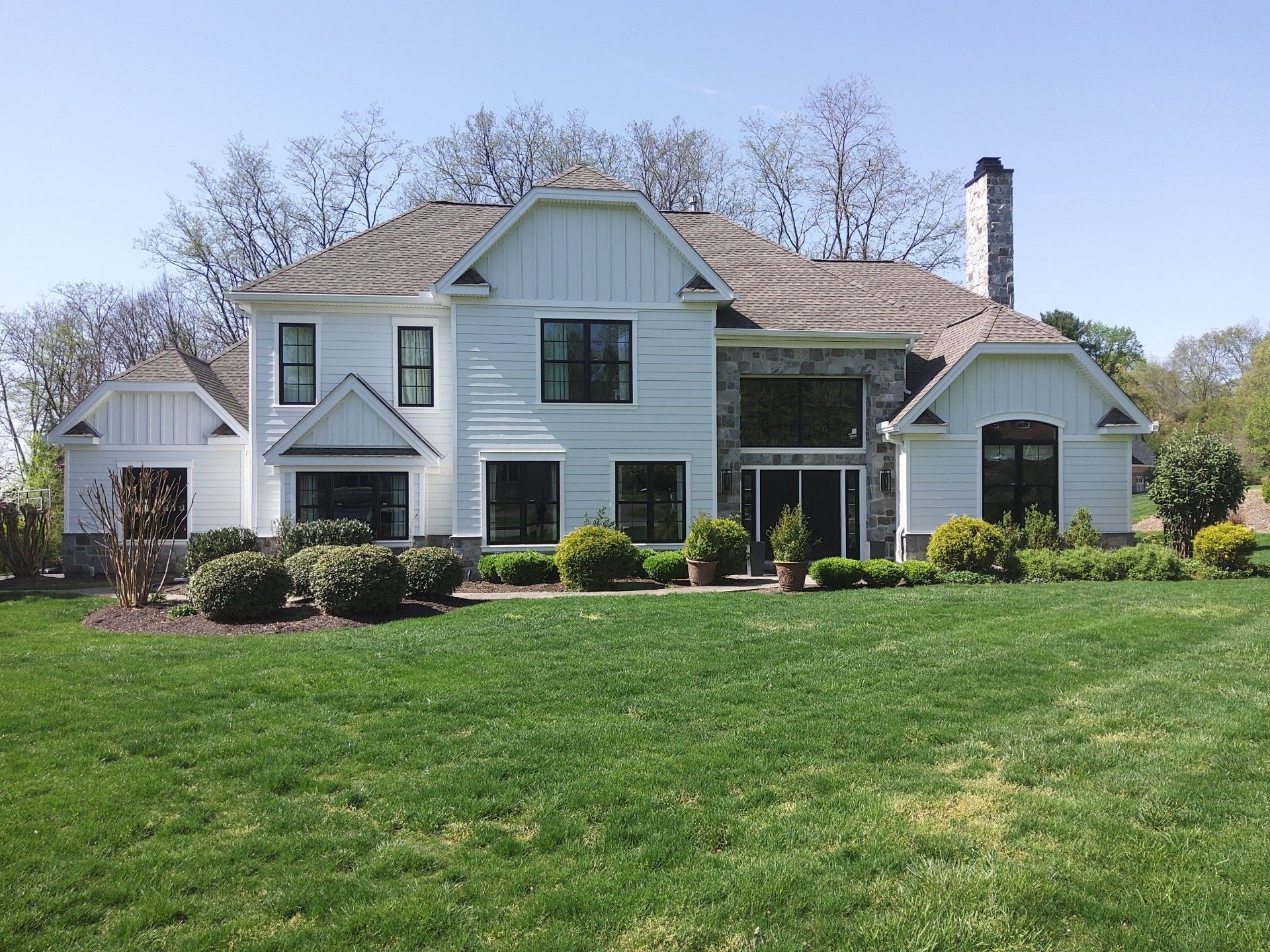 White house with green trim and large lawn under a clear blue sky