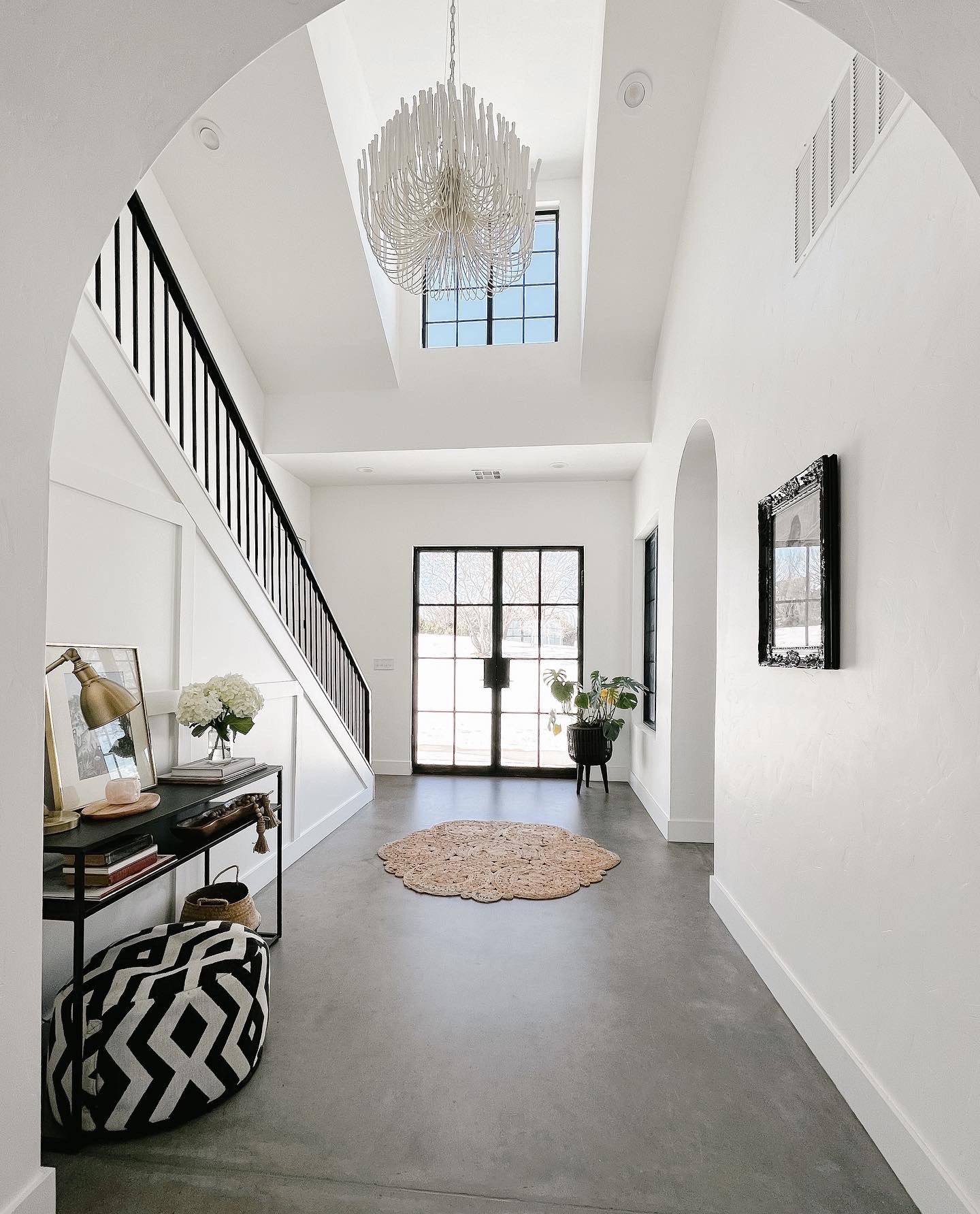 A rustic game room with a pool table, an antler chandelier, wooden shelves, and a patterned rug on a hardwood floor.