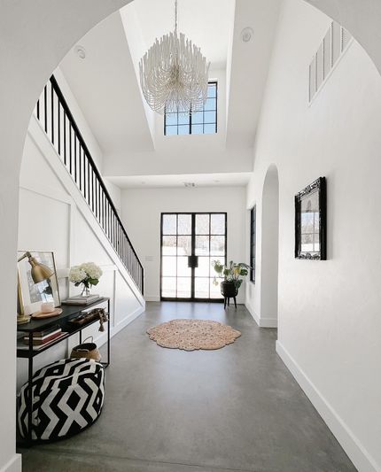 A rustic game room with a pool table, an antler chandelier, wooden shelves, and a patterned rug on a hardwood floor.