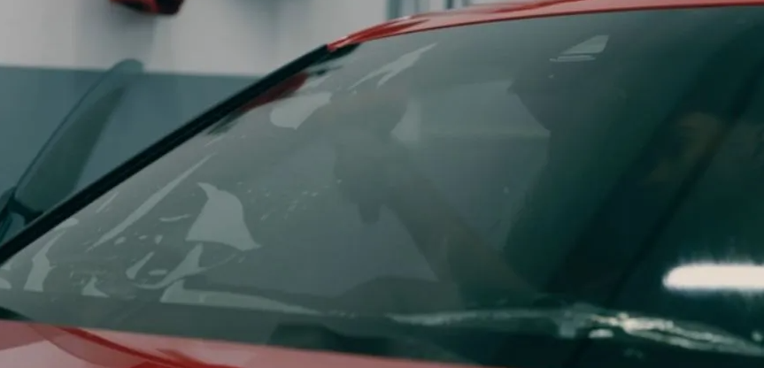 Windshield of a red car with a person visible inside.