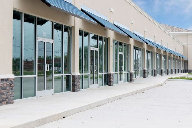 Empty commercial storefronts with reflective glass windows and blue awnings.