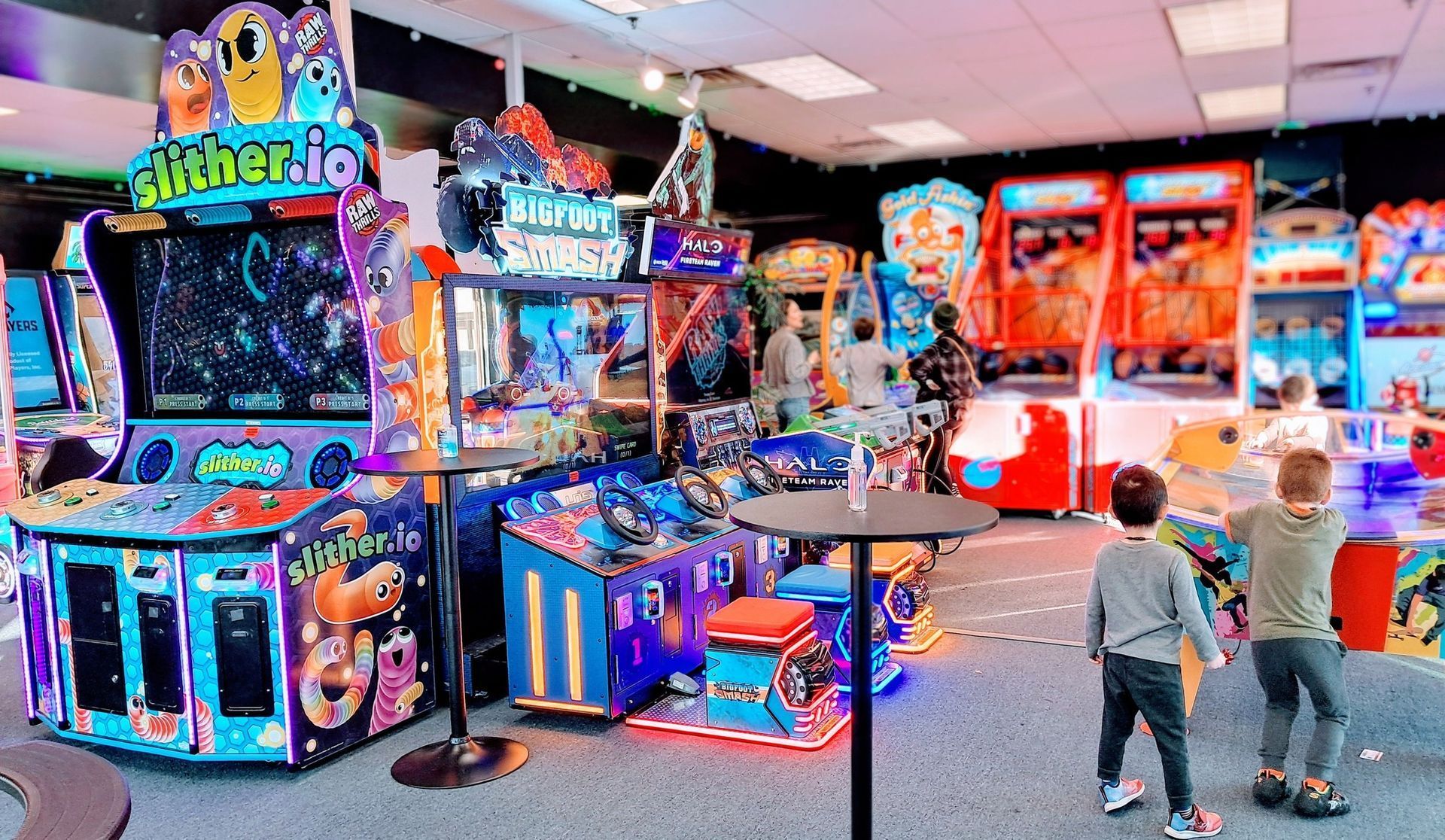 Air hockey table with a puck, arcade setting with people blurred in the background.
