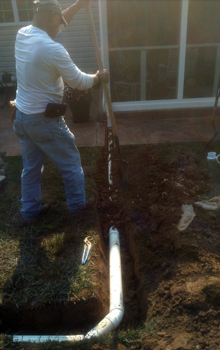 a man is digging a hole in the ground to install a pipe