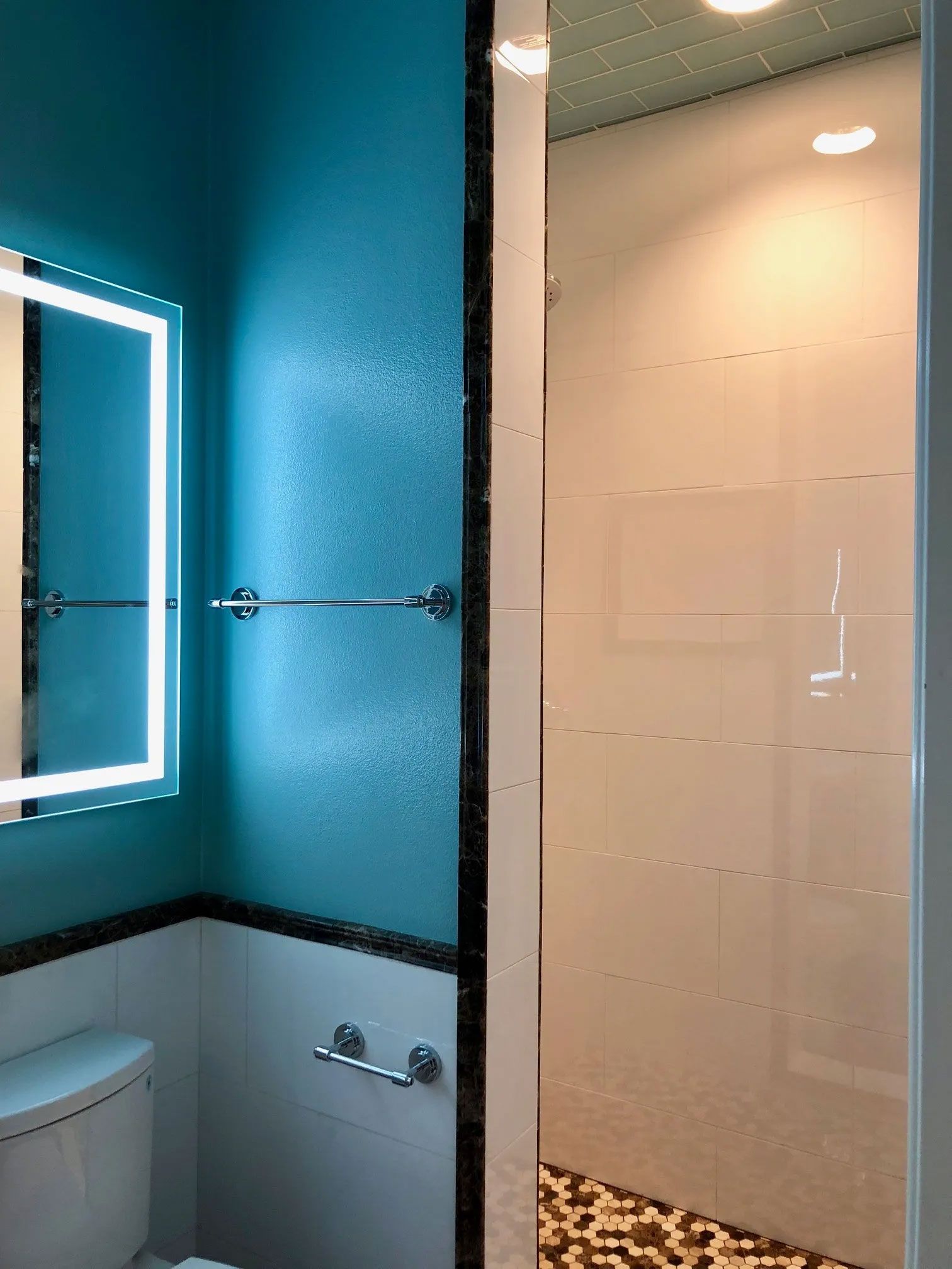A bathroom with a toilet , mirror and shower.
