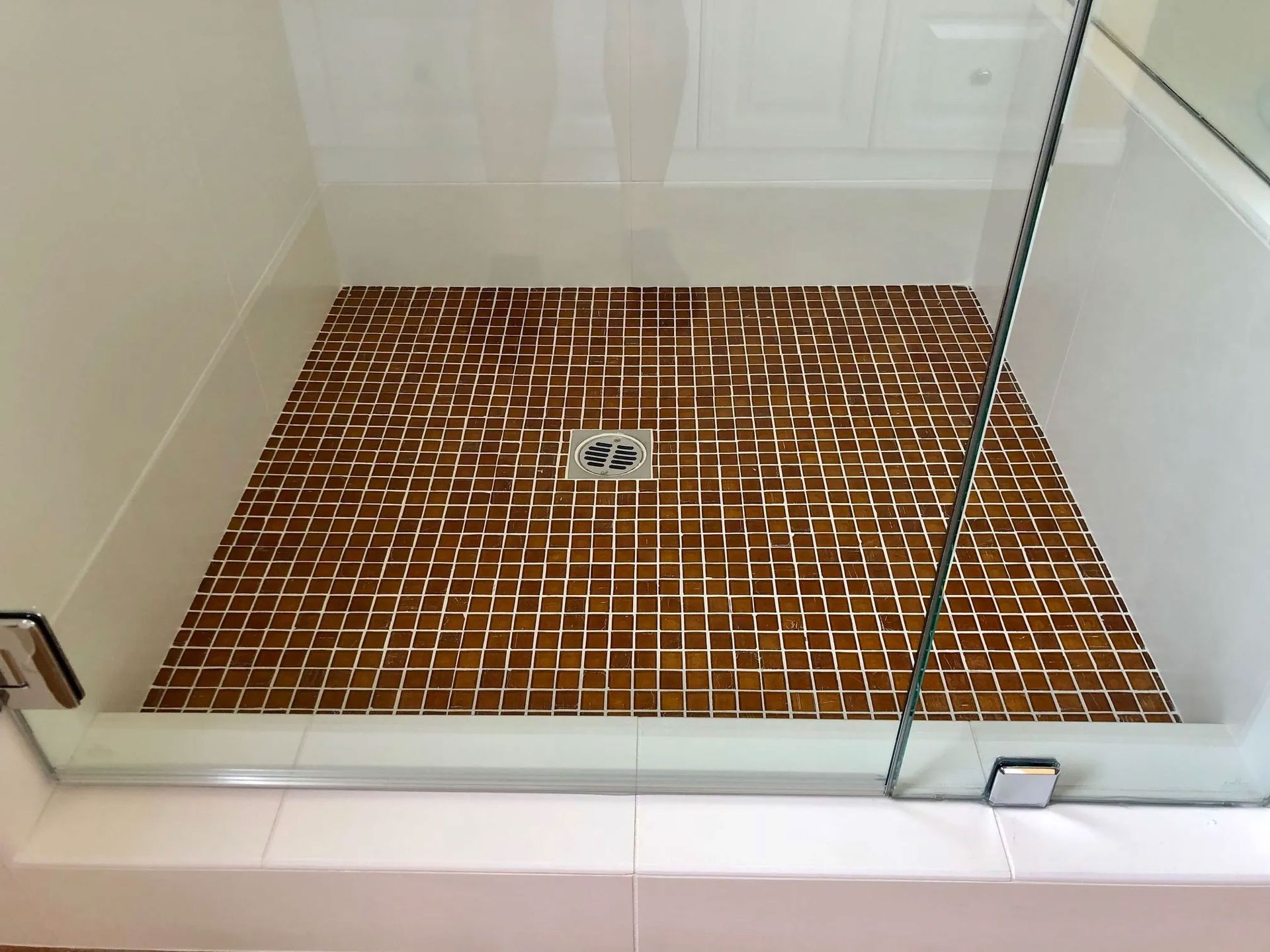 A shower stall with a tiled floor and a glass door