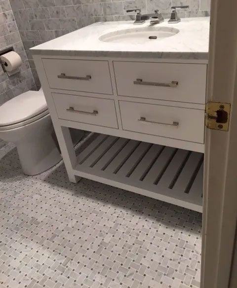 A bathroom with a toilet , sink and drawers