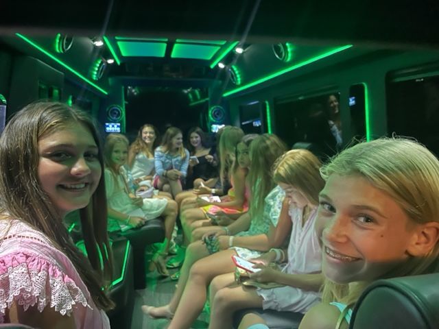 a group of young girls are sitting on a bus with green lights