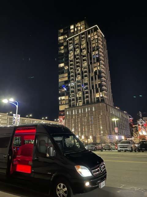 a black van is parked in front of a tall building at night