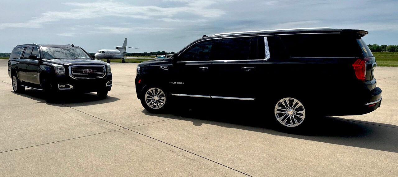 two black suvs are parked next to each other on a runway