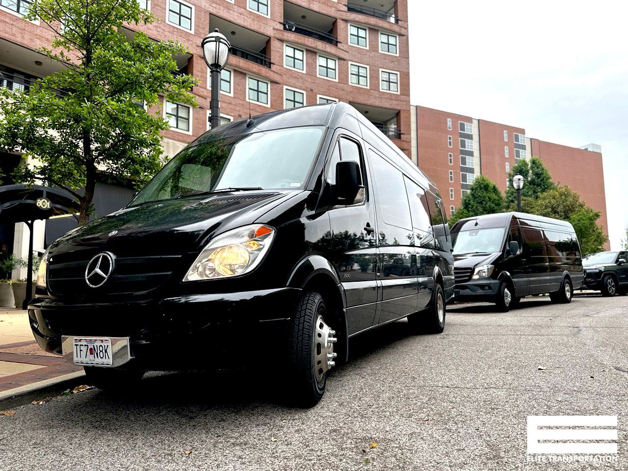a black mercedes sprinter van is parked on the side of the road in front of a building