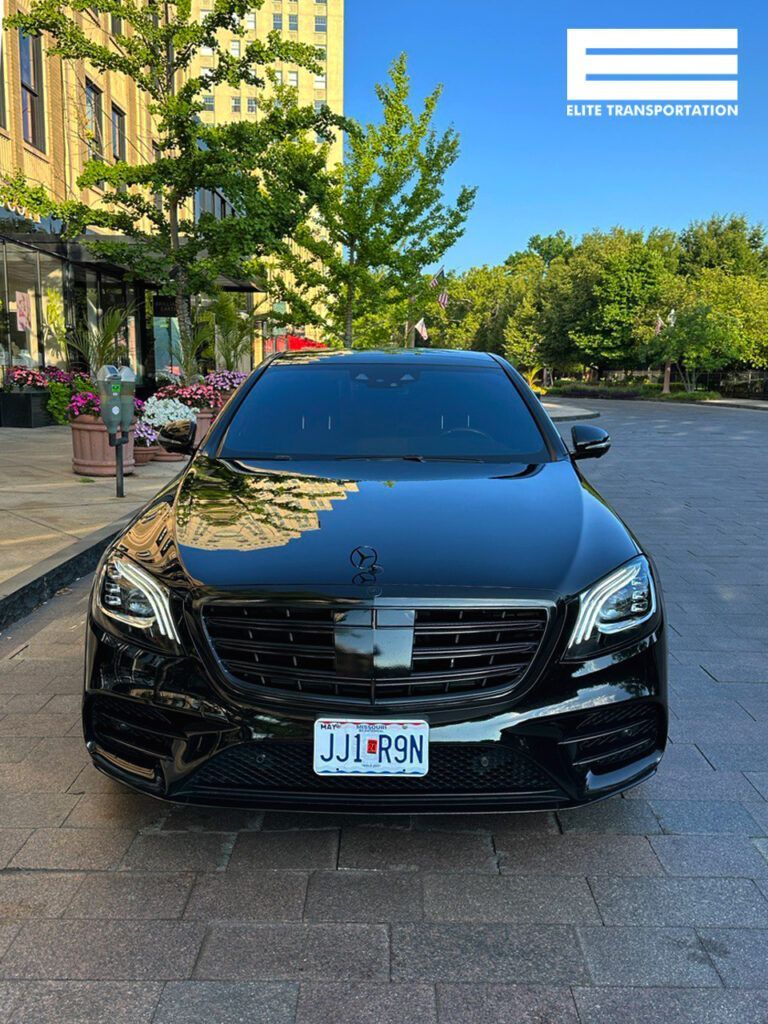 a black mercedes benz is parked on a sidewalk in front of a building