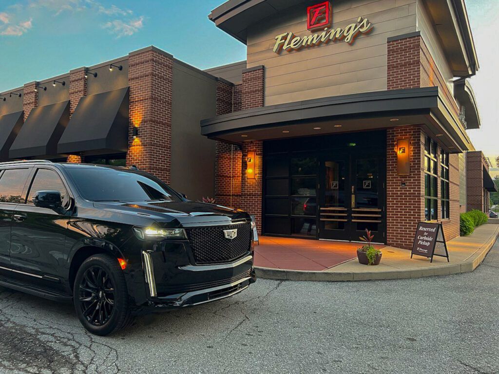a black car is parked in front of a restaurant