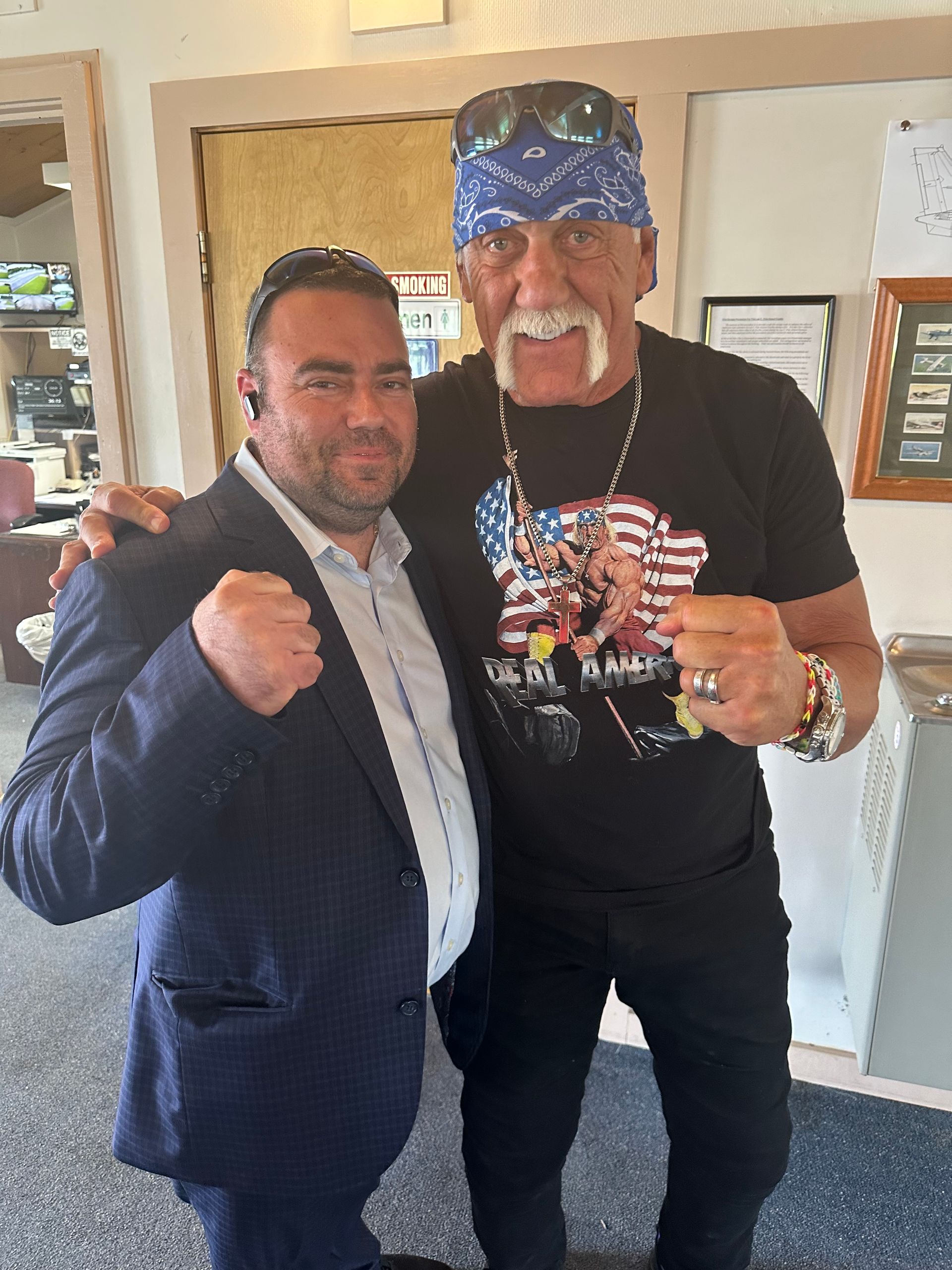 Hulk hogan is posing for a picture with a man in a suit